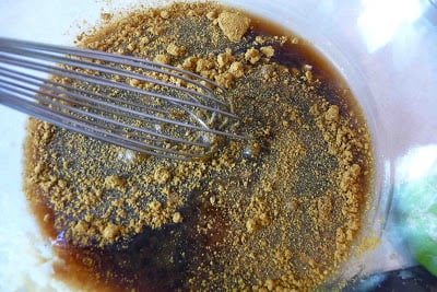 A whisk in a mixture of soy sauce and curry powder.