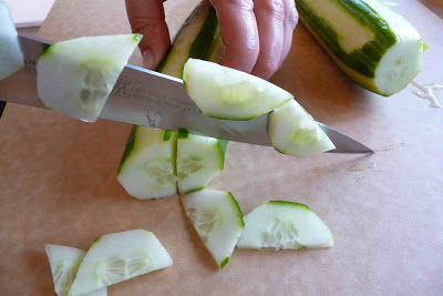 Slicing an English cucumber into half-circles.
