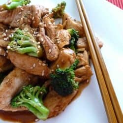 Chicken and broccoli stir with chopsticks on a white plate.