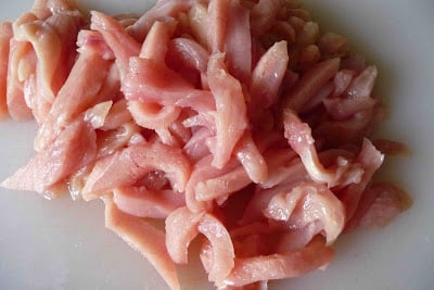 Strips of raw chicken on a cutting board.