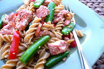 Teriyaki sauce pasta with salmon and vegetables on a blue plate.