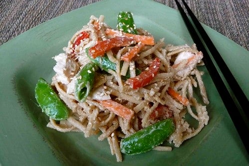 Noodles, chicken and vegetables on a green plate.
