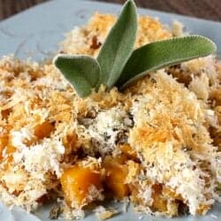 Butternut squash grating topped with breadcrumbs on a blue plate.