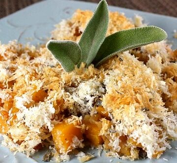 Butternut squash grating topped with breadcrumbs on a blue plate.