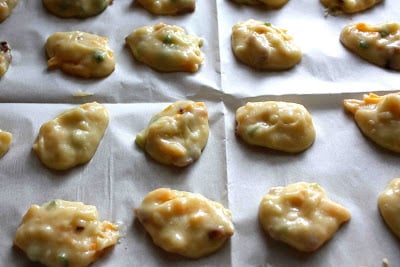 Raw cheese puffs on a baking sheet.