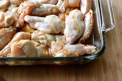 Raw chicken wings and drumettes in glass baking dish with soy sauce mixture.