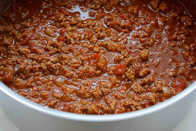 Cooked ground turkey and crushed tomatoes in a saucepan.