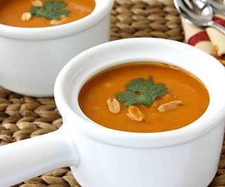 Sweet potato and peanut soup in a white crock with a handle.