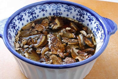 Dried mushrooms soaking in a blue and white bowl.