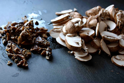 Raw and rehydrated mushrooms on a black cutting board.