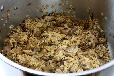 Cooked mushrooms and orzo in a saucepan.