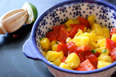 Mango salsa in a bowl, with a lime half on the side.