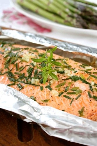 Salmon fillet in foil, topped with fresh herbs.