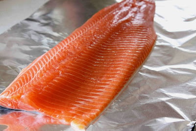 Raw salmon fillet on a sheet of foil.