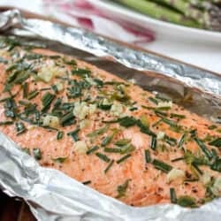 Salmon fillet in foil, topped with herbs.