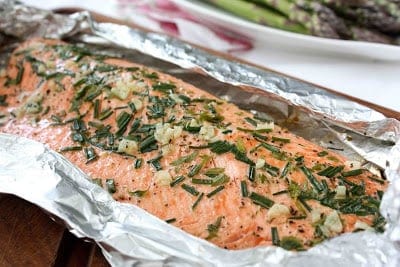 Salmon fillet in foil, topped with fresh herbs.