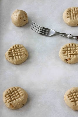 Raw cashew cookies on a baking sheet lined with parchment paper.