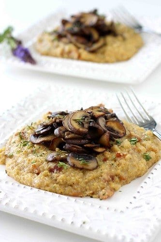 Polenta topped with sautéed mushrooms on a white plate.