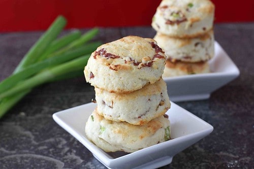 Cream biscuits with prosciutto pile on a white plate.
