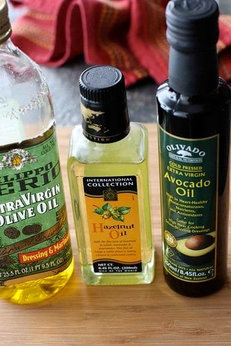 Three bottles of cooking oil on a cutting board.