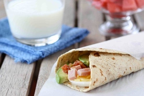 A tortilla wrap filled with ham, avocado and salsa.