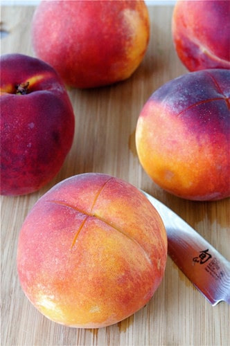 Peaches and knife on a cutting board.