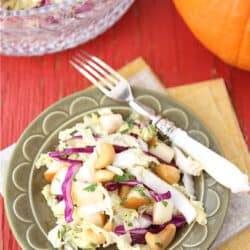 Slaw with cashews and pear on a green plate.