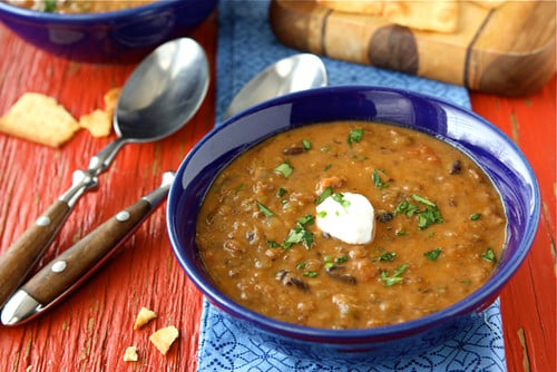 Soup with lentils and black beans in a blue bowl.