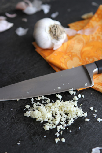 Minced garlic on a black cutting board.