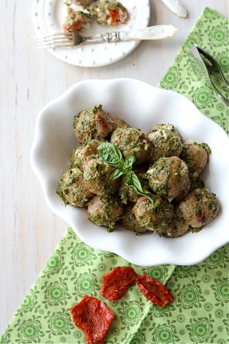 Turkey meatballs coated in pesto in a white bowl.