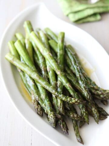 Spears of roasted asparagus on a white platter.