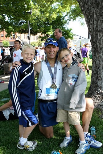 Man in running gear, with two young kids.