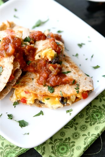 Breakfast quesadilla topped with salsa on a white plate.