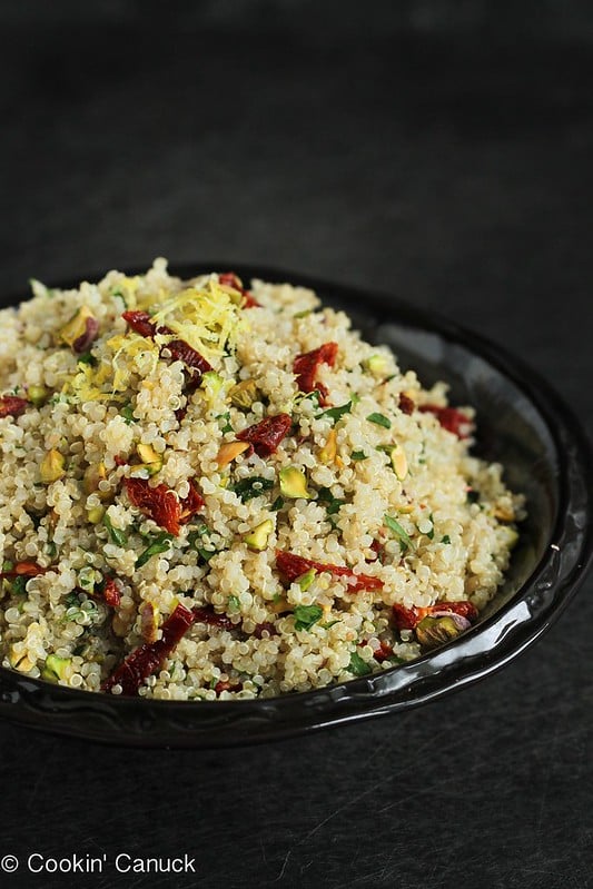 Lemon quinoa salad with pistachios and sun-dried tomatoes in a black bowl.