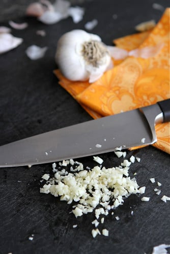Minced garlic on black cutting board.
