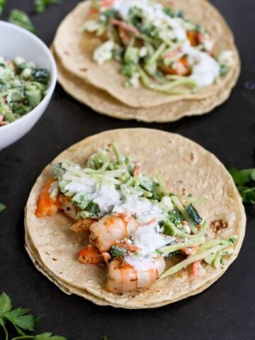 Large cooked shrimp and broccoli slaw in tacos.