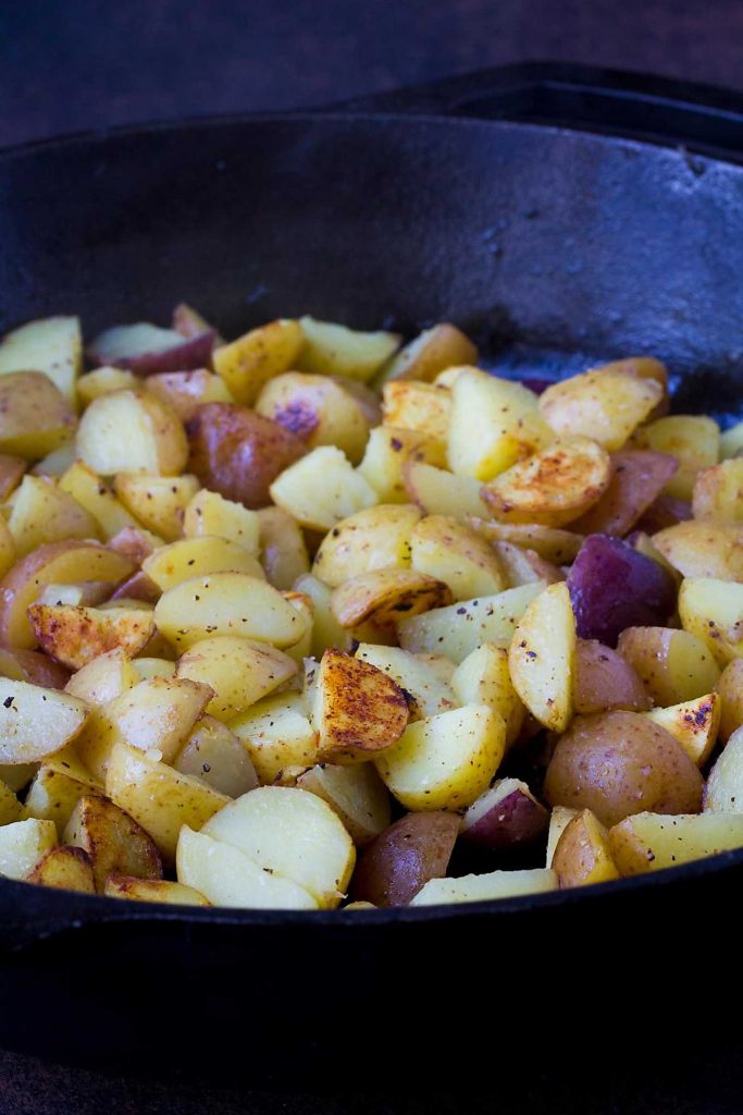 Breakfast potato hash, turning golden brown in a cast iron skillet.