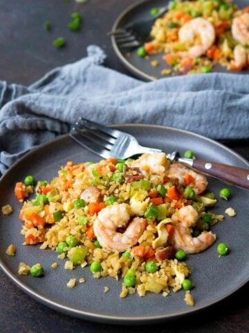 Shrimp and cauliflower fried rice with vegetables on a gray plate.