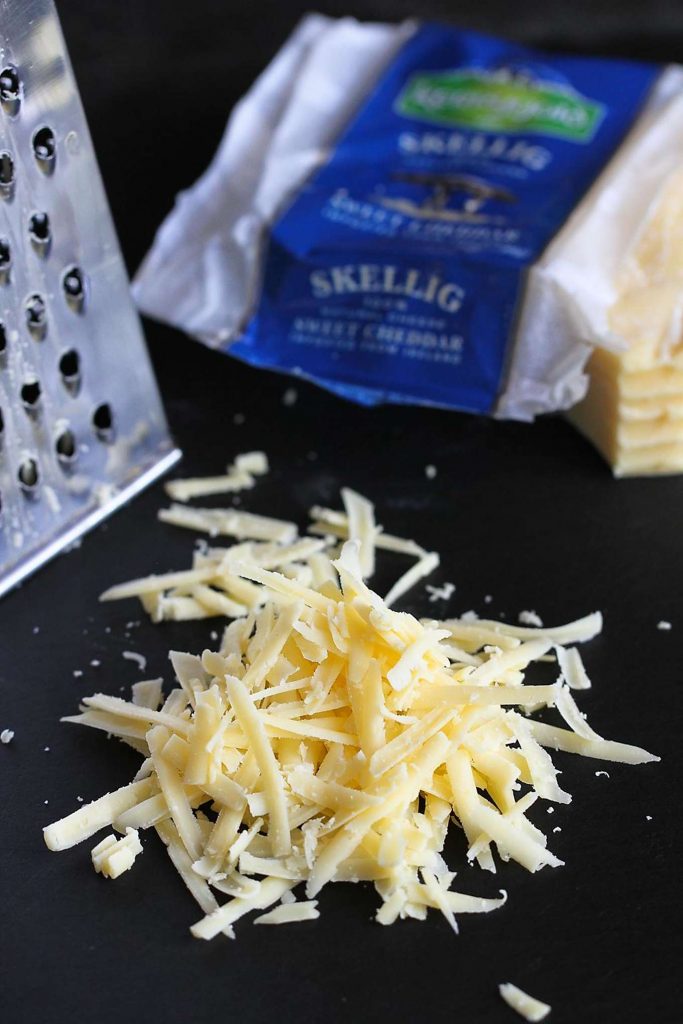 Grated Kerrygold Skellig cheese on a cutting board.