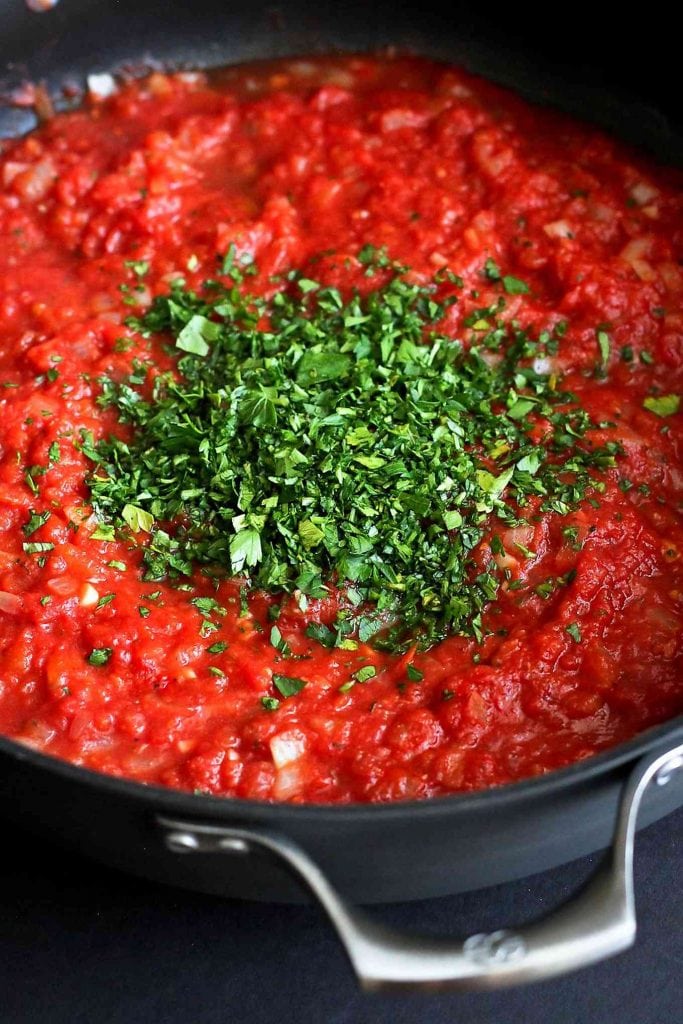 Homemade tomato sauce in a skillet, with fresh parsley sprinkled over top.