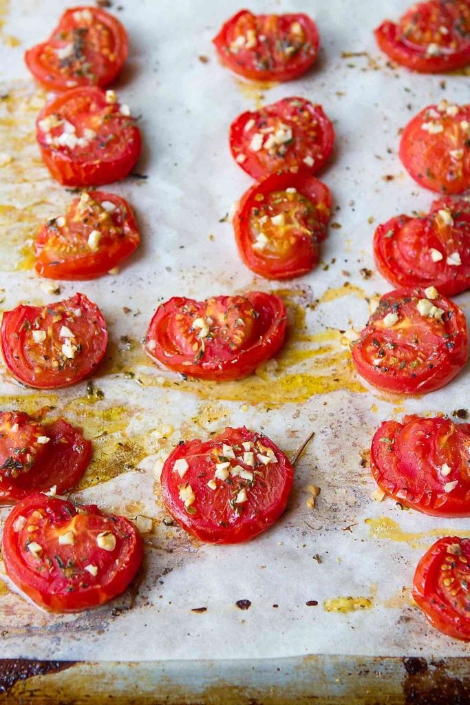 Roasted tomatoes, with garlic and oregano on a baking sheet.