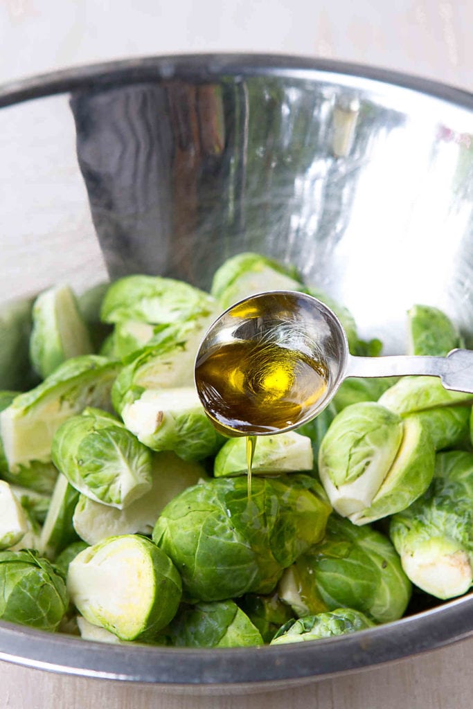 Brussels sprouts in a bowl, drizzled with olive oil.