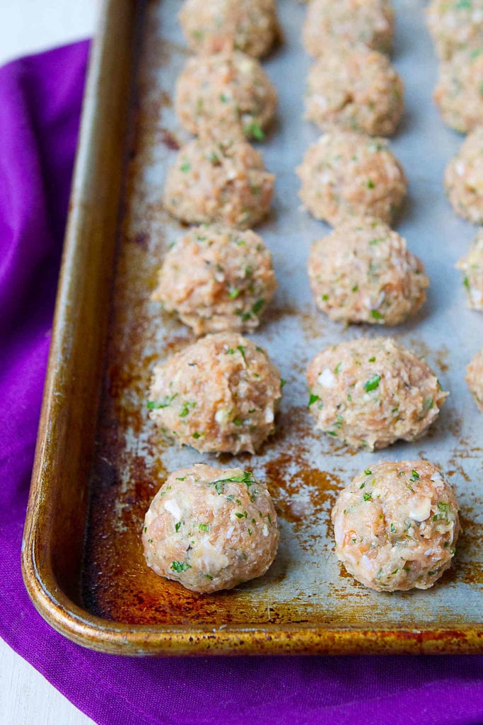 Chicken and turkey meatballs on a baking sheet, ready to be cooked.