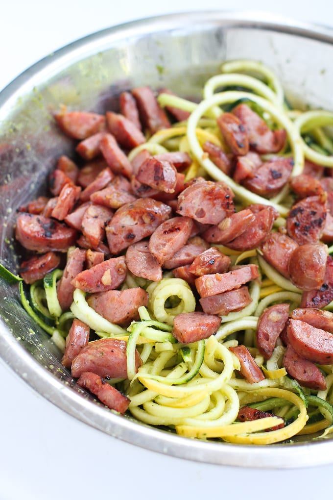 Zucchini noodles and cooked chicken sausage in a serving bowl.