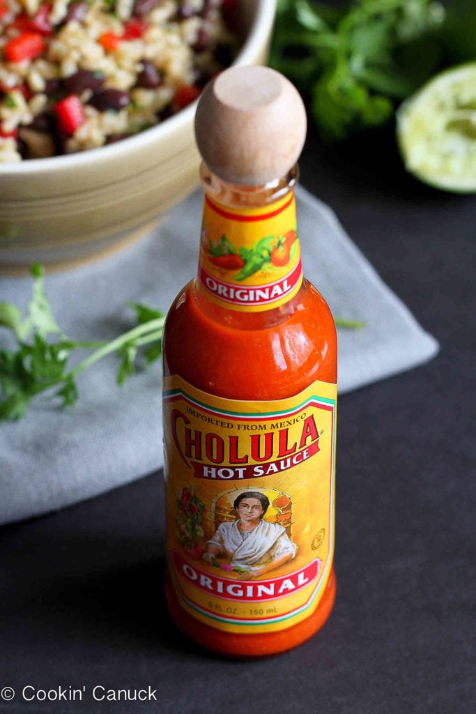A bottle of Cholula hot sauce on a black background.