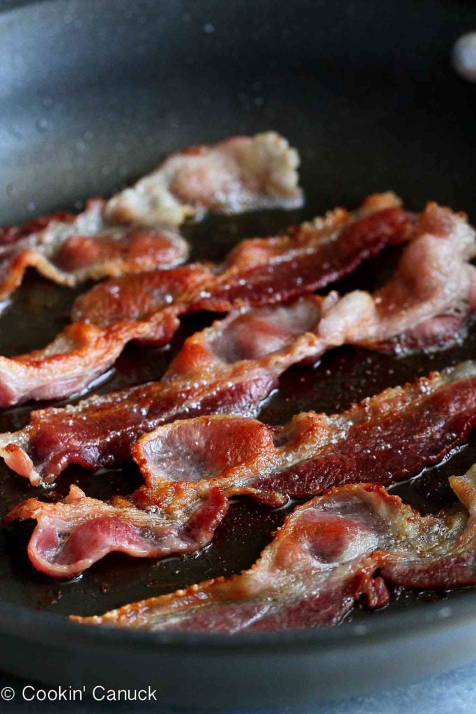 Bacon slices cooking in a nonstick skillet.