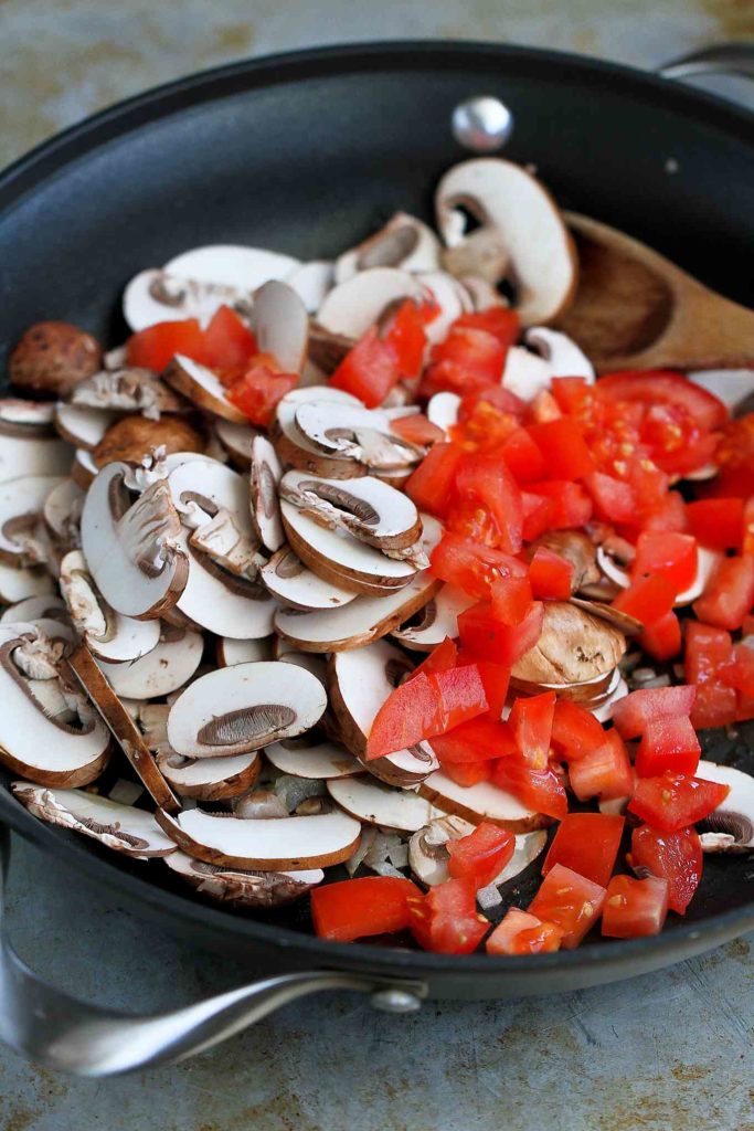Sliced mushrooms and tomatoes in a large skillet.