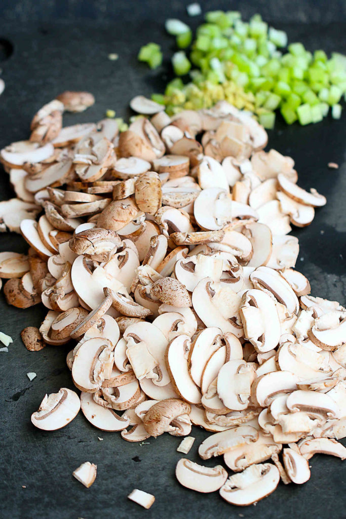 Sliced mushrooms and celery on a cutting board.