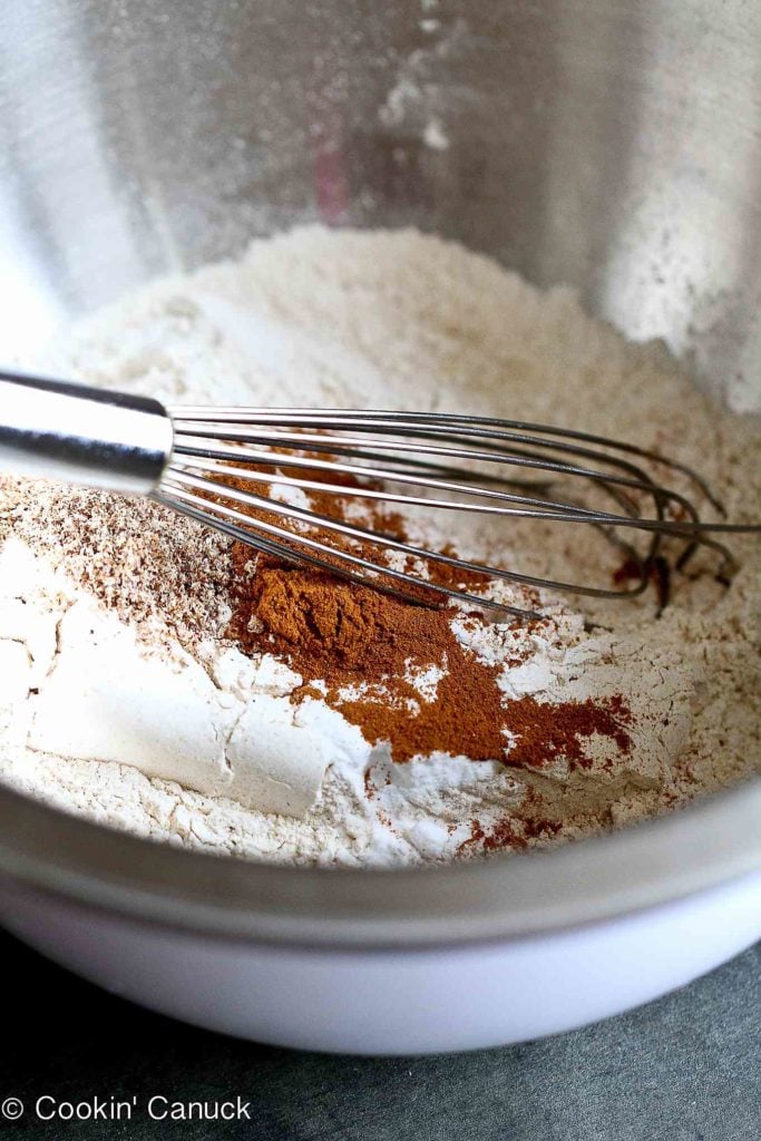 Whole wheat pastry flour, cinnamon, nutmeg and baking soda in a bowl, with a whisk.