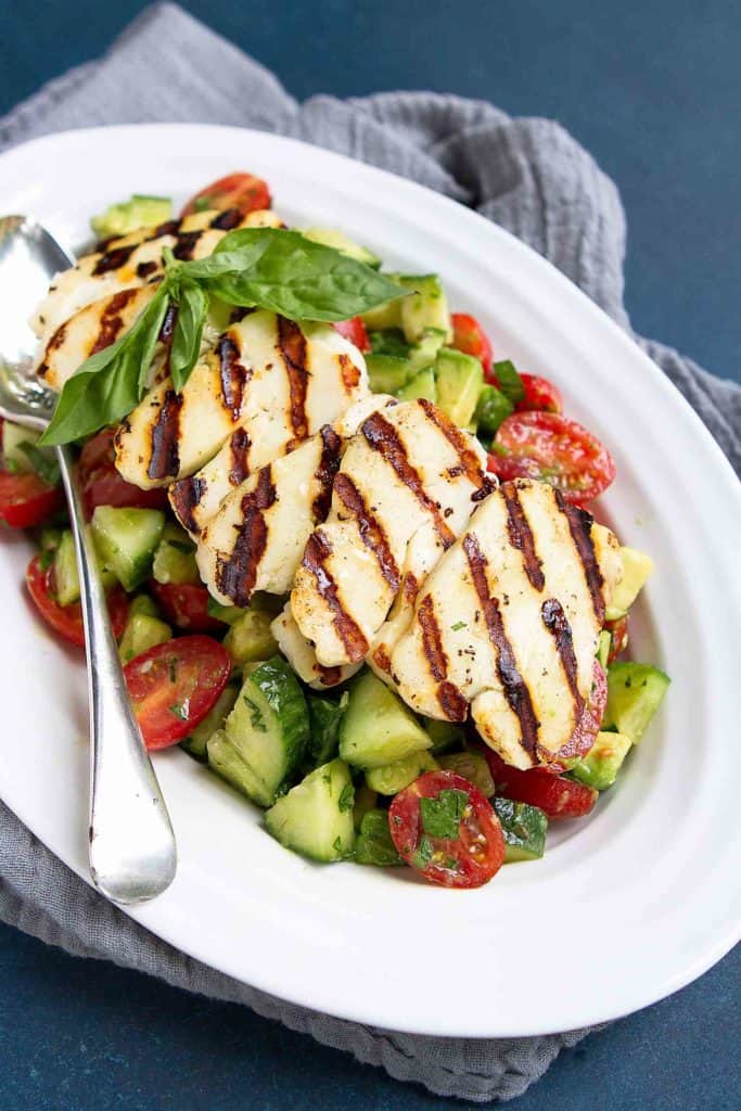 Chances are you won't be able to eat just one serving of this easy Cucumber Tomato Avocado Salad. The grilled halloumi cheese on top makes it utterly addictive. 102 calories and 3 Weight Watchers Freestyle SP #halloumi #avocado #salad #weightwatchers